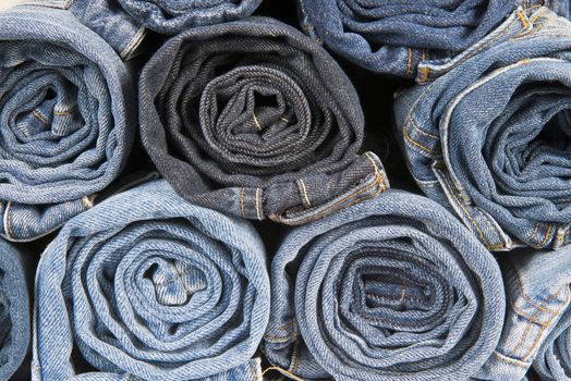 Rolls of different worn and old blue jeans stacked