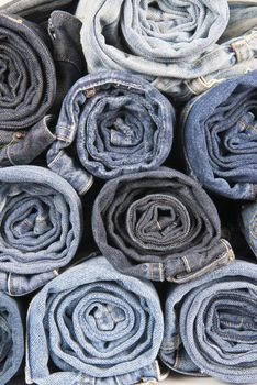 Rolls of different worn and old blue jeans stacked