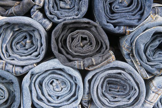 Rolls of different worn and old blue jeans stacked