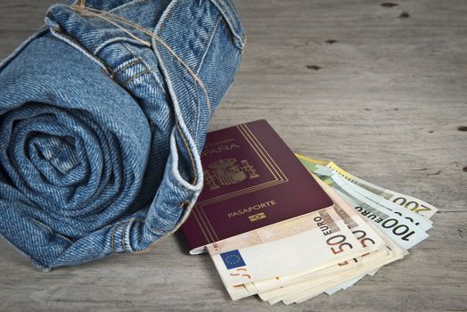 Rolled jeans, a passport and a lot of money on a wooden background