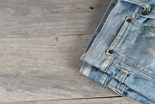 Old worn blue jeans over an old wooden background