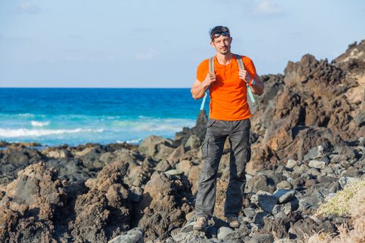 Sports young man with backpack. in the background of the sea