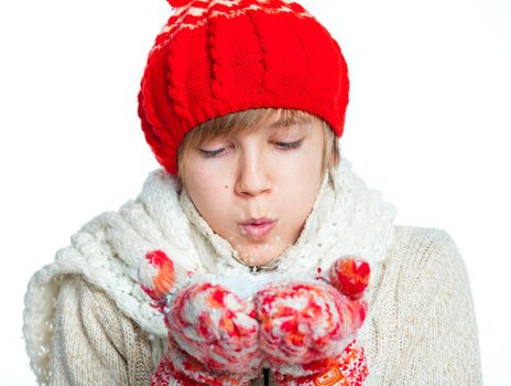 Portrait of young smiling cute teenager in a red hat and mittens with snow, isolated on white