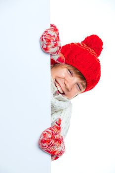 Portrait of young smiling cute teenager in a red hat and mittens looking at a blank board, isolated on white