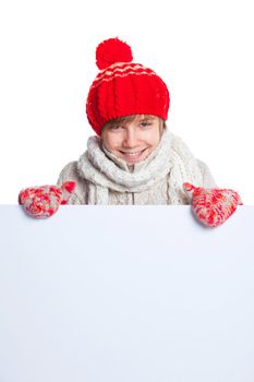 Portrait of young smiling cute teenager in a red hat and mittens looking at a blank board, isolated on white