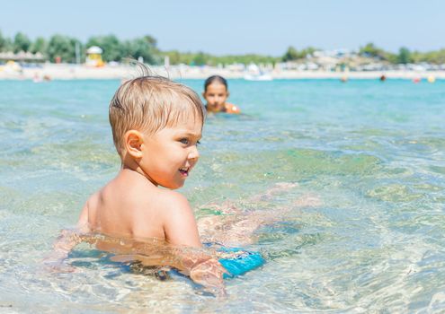Happy kids. Sister and brother playing and swimming in the transparent sea