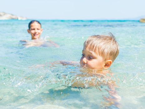 Happy kids. Sister and brother playing and swimming in the transparent sea