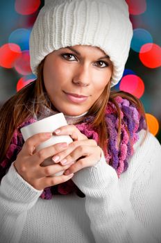 Young woman drinking a hot drink from a white mug