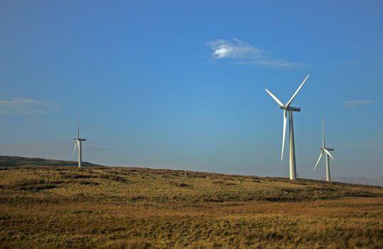 Field with energy producing windmills on top a hill