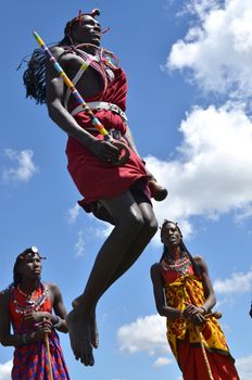 Village Masai Mara, Kenya - October 17, 2011: A yuong Masai welcomes tourists with the traditional jumping ceremony .