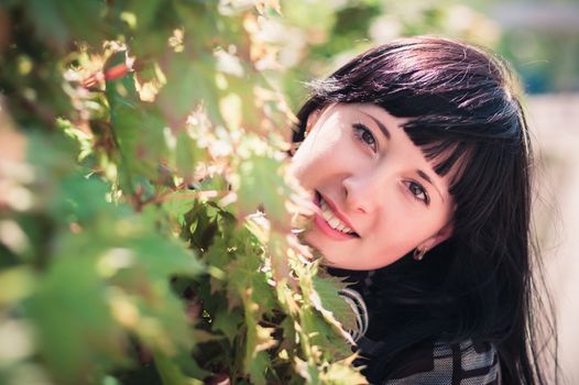 Young woman standing near a maple with lush foliage