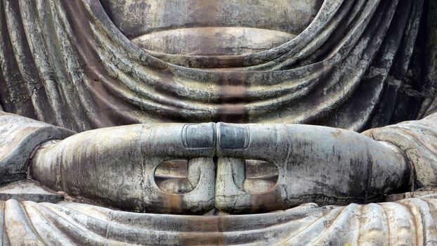 detailed image of Buddha's sculpture hands in peaceful pose; focus on hands