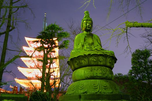 night image of Buddha statue and five storey pagoda on backward in Asakusa, Tokyo; focus on statue