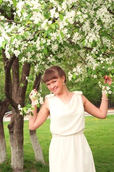 beautiful young brunette woman with the apple tree on a warm summer day