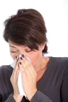 Woman suffering from a cold and flu blowing her nose on a handkerchief, head and shoulders studio portrait on white Woman sufering from cold and flu blowing her nose on a handkerchief, head and shoulders studio portrait on white
