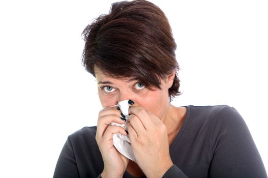 Unhappy woman with a cold blowing her nose on a handkerchief while looking up at the camera isolated on white