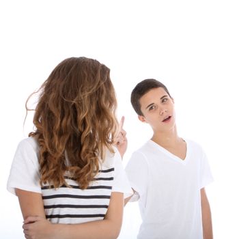 Sibling rivalry and jealousy as a young teenage girl looks back at her brother who is arguing and shaking a finger at her from behind isolated on white