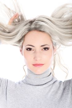 Ethereal soft head and shoulders portrait of a beautiful dreamy woman flicking her blonde hair high into the air isolated on white Ethereal soft portrait of a beautiful dreamy woman flicking her blonde hair high into the air isolated on white