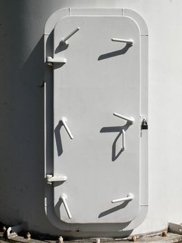white metallic door  of the marine ship with many hand locks