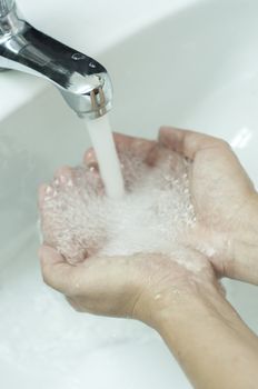 Close-up of human hands being washed under pure water from tap