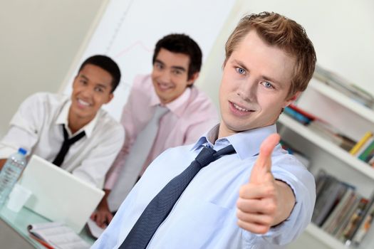 Young businessman giving thumbs-up during meeting