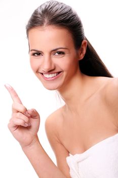 Beautiful and Smiling woman in towel pointing with one finger up in the air
