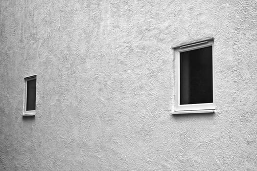 Stark white external wall with two small, plain glass windows