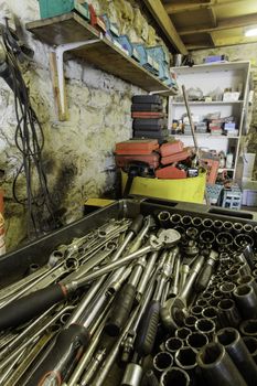 Garage interior with a range of tools and storage on shelving and an extensive socket set in the foreground