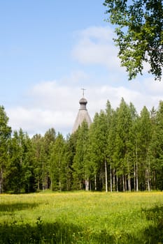 A traditional wooden russian church back from a forest
