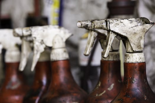 Detail of the heads a row of well used and dirty spray bottles, with intentional shallow depth of field