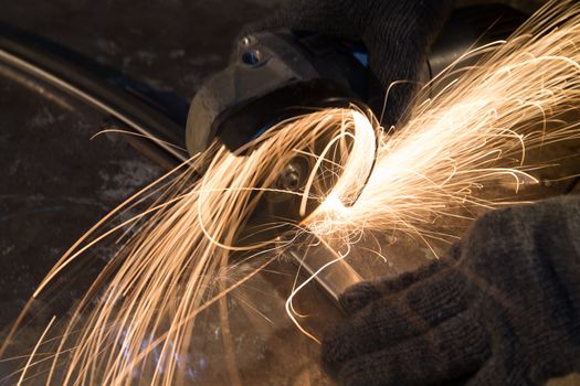 Worker cutting metal with many sharp sparks