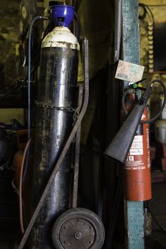 Equipment in a workshop including a gas cylinder mounted on a trolley for portability and a fire extinguisher mounted on the wall