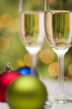 Beautiful Various Colored Christmas Ornaments and Champagne Glasses on Snow Flakes In Front of an Abstract Background.