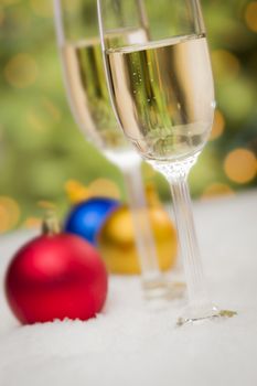 Beautiful Various Colored Christmas Ornaments and Champagne Glasses on Snow Flakes In Front of an Abstract Background.