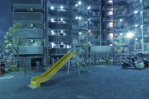 blue tinted city playground by night near big residential building