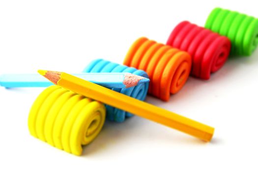 An array of colored plasticine rolls with two colored pencils in a crossed position