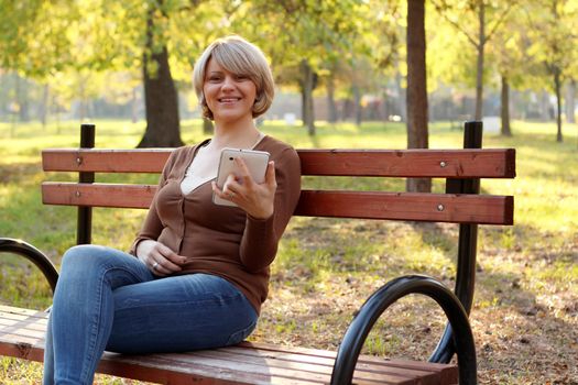 beautiful woman sitting in park and play with tablet