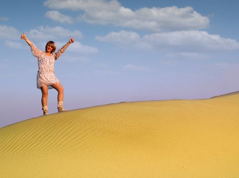 beautiful woman with thumbs up standing on desert dune