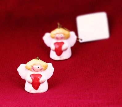 Cute Christmas angels with red hearts and copy space on red background