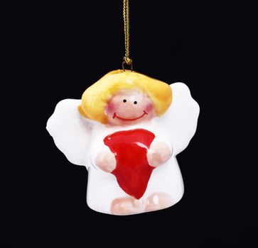 Cute Christmas angel with red heart hanging against black background