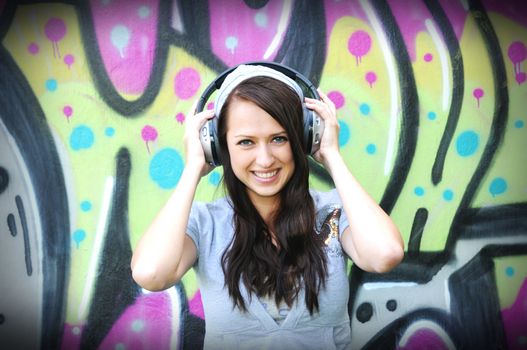 Young and beautiful girl posing against wall with graffiti