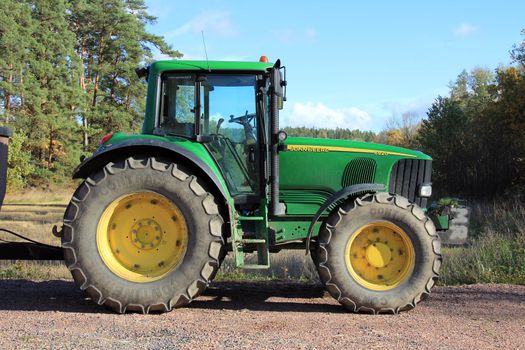 SALO, FINLAND - OCTORER 7, 2012 - John Deere 6920 tractor by field. Due to heavy rainfall and flooding, the harvesting season is several weeks late and estimated 5-10% of cereal crops and 10-15% of oleiferous plant crops are lost in Finland.