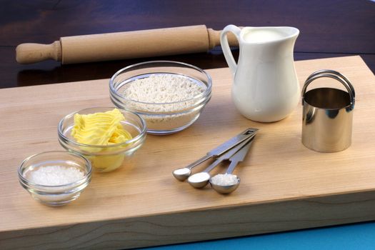 dough ingredients and kitchen utensils on wood cutting board