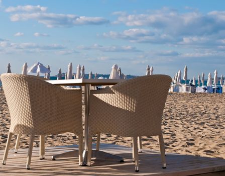 View of the beach with street cafe , table, chair , loungers and umbrellas.