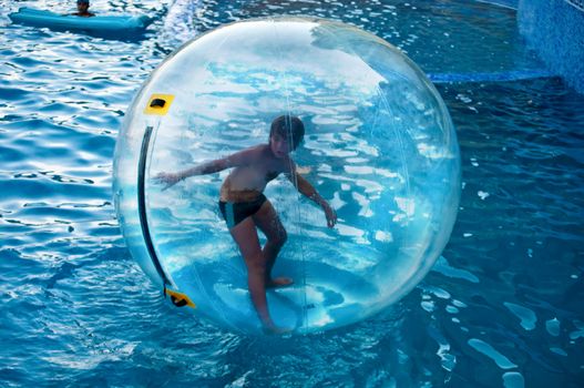 Boy in the air ball in the water in the pool.