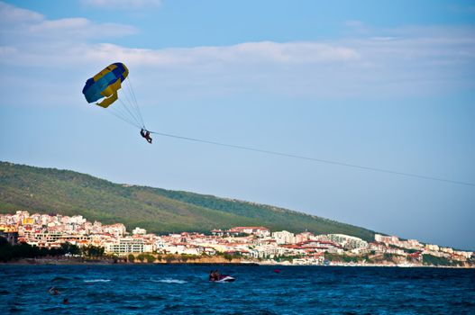 Colorful hang glider in sky over blue sea .