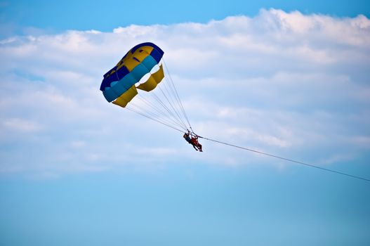 Colorful hang glider in sky over blue sea .