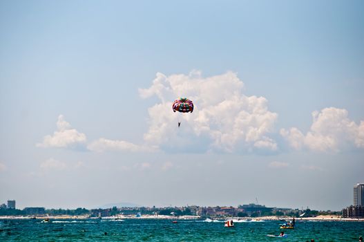 Colorful hang glider in sky over blue sea .