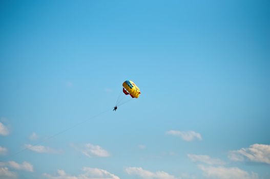 Colorful hang glider in sky over blue sea .