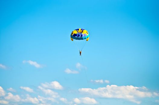 Colorful hang glider in sky over blue sea .